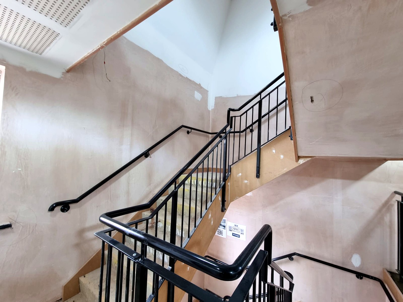 Wall-mounted steel handrail with scrolled end on communal stairs, Radlett